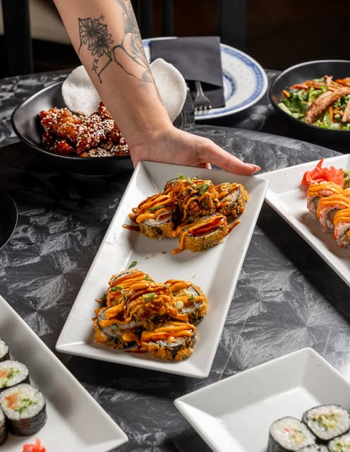 Πιατέλα με sushi rolls που σερβίρεται σε γεμάτο τραπέζι