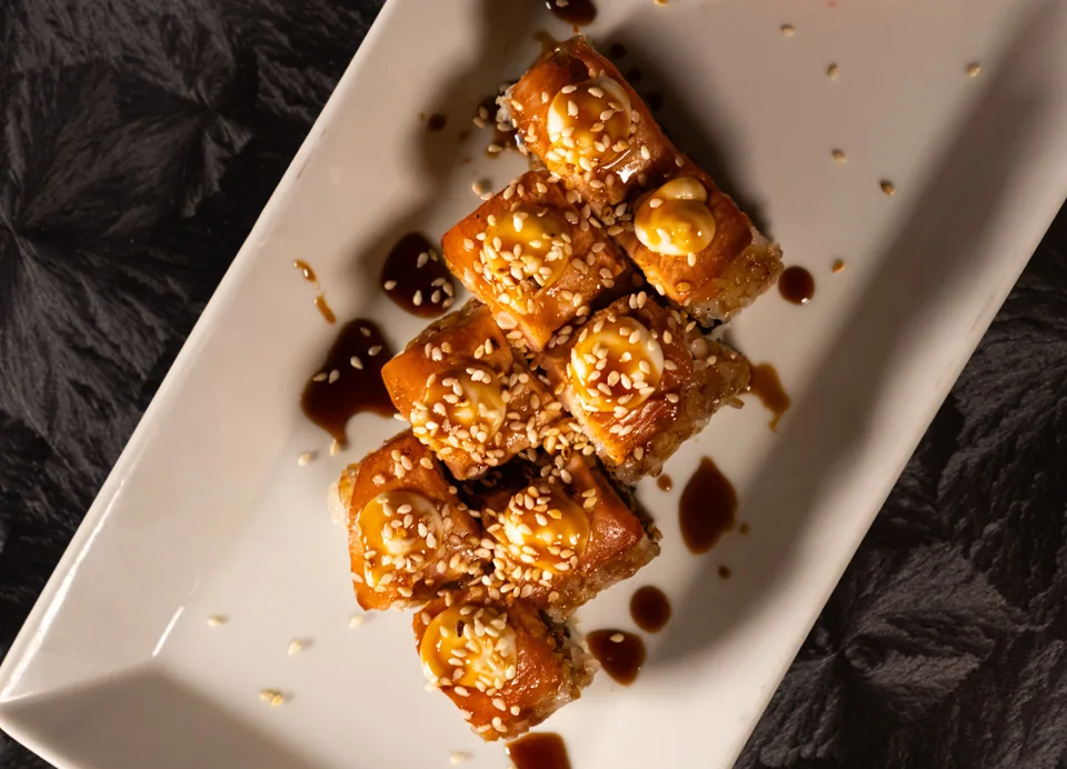 Sushi rolls με σάλτσα και σουσάμι σε λευκή πιατέλα, φωτογραφημένα από ψηλά