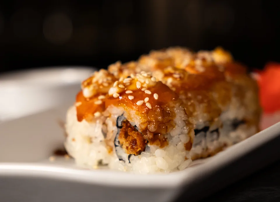 Κοντινή λήψη sushi rolls με σάλτσα και σουσάμι σε λευκή πιατέλα