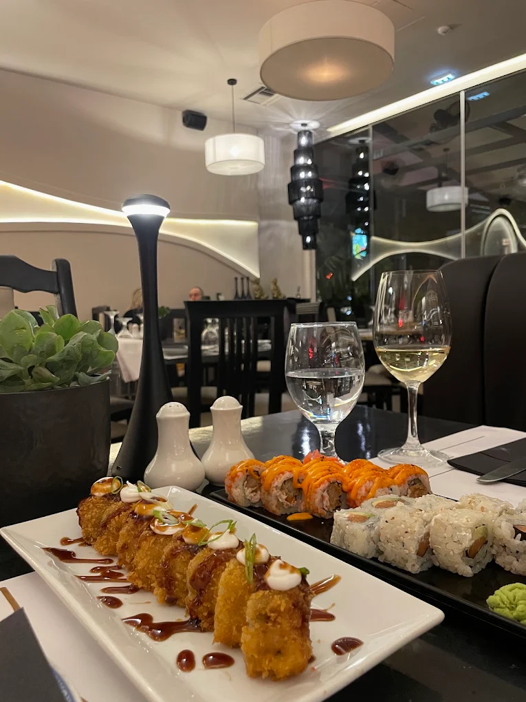 Πιατέλες με sushi και ποτήρια κρασιού σε τραπέζι στη σάλα του Nama